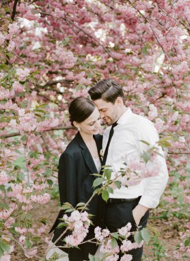 Bir çift, güzel bir bahar günü boyunca yemyeşil, pembe kiraz çiçekleriyle çevrili hassas bir anın tadını çıkarır..