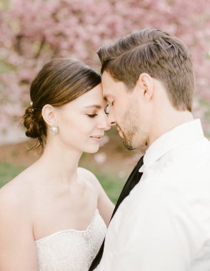 İki insan, güzel çiçeklerle çevrili, bir bahar günü aşklarını kutlayan yakın bir kucaklaşma için eğilir..