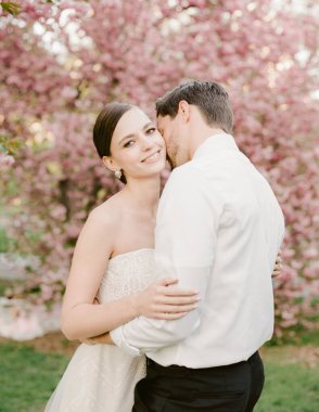 Neşeli bir çift, baharda canlı pembe çiçeklerle çevrili özel bir anı paylaşır. Aşklarını kutlarlar..