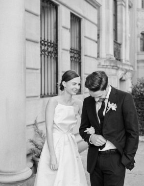 Bir gelin ve damat birbirlerine samimi bir şekilde gülümserler, aşklarını klasik bir mimari zemine karşı kutlarlar..