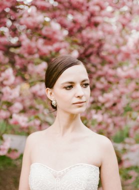 Dantelli gelinlik giymiş bir gelin zarif pembe çiçeklerle, neşeli bir anı yakalar..