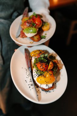 Garsonlar, canlı bir yemek atmosferinde taze sebze ve süslemelerle güzel düzenlenmiş yemekler sunar..