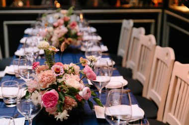 Çiçek süslemeleri ve cam süslemelerle dolu zarif bir yemek masası..