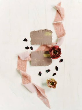 Güzel düğün davetiyelerine yumuşak kurdeleler ve açık ahşap arka planda kurumuş çiçek aksanları eşlik ediyor..