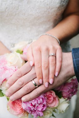 Çiftler, alyanslarını gösterip pembe çiçeklerle dolu güzel bir buket tutarak aşklarını kutluyorlar..