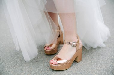 Göz kamaştırıcı yüksek topuklu sandaletler, neşeli bir kutlama sırasında açık havada giyilen güzel bir düğün elbisesinin parçası olarak parlıyor..