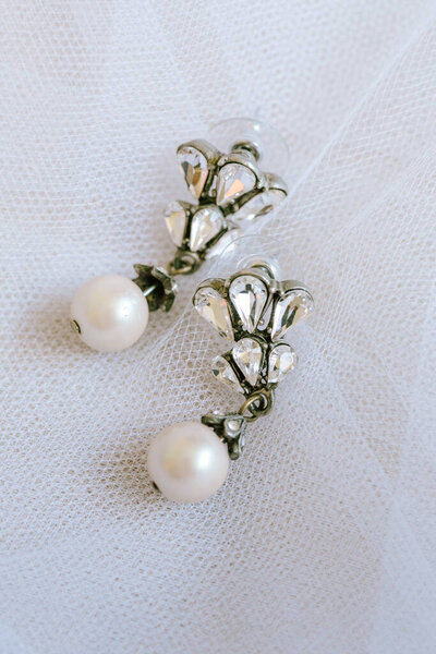 Vintage earrings with pearls and crystals, elegantly displayed on soft fabric, perfect for special occasions.