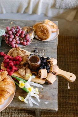 Hamur işleri, meyveler ve reçel ahşap bir masada ustalıkla düzenlenir ve davetkar bir hava yaratır..
