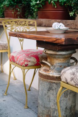 Kırsal bir masa, renkli sandalyeler ve canlı hissetmek için saksı bitkileri olan rahat bir yemek alanı..