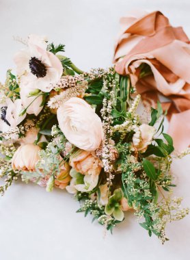 Canlı bir anemon buketi, ranunculus ve yeşillik, saten bir kurdele ile herhangi bir durum için zarifçe bağlanmış..