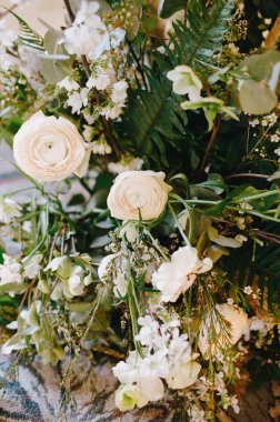 Hassas beyaz güller ve çeşitli yeşillikler düğün ve etkinlikler için muhteşem bir çiçek dekoru oluşturur..