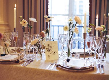 Mumlar ve çiçeklerle dolu güzel bir yemek masası misafirler için sıcak ve davetkar bir ortam yaratıyor..