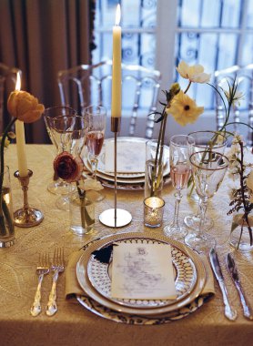 Güzel düzenlenmiş bir yemek masasında gece rahat bir ortamda zarif mumlar ve taze çiçekler bulunur..