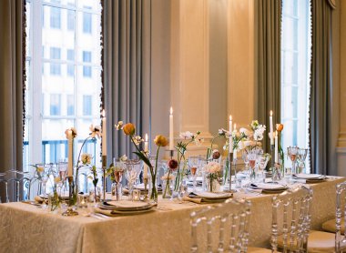 Güzel düzenlenmiş bir masa, çiçekler, mum ışığı ve güzel sofra takımları içerir. Özel bir akşam toplantısı için mükemmeldir..