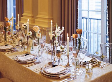 Çiçekli ve mumlu güzel bir yemek masası. Akşam kutlaması için sıcak bir ortam yaratıyor..