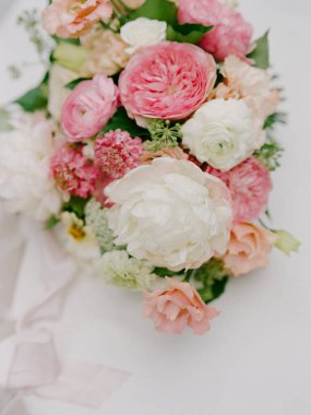 Pembe ve beyaz çiçeklerle dolu çarpıcı bir buket, bahar düğünü için mükemmel, yumuşak bir yüzeyde duruyor..