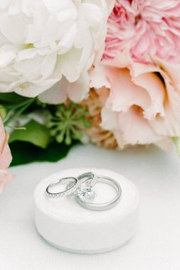 İki alyans yumuşak bir mindere yerleştirilir, yakınlardaki güzel bir çiçek aranjmanıyla aksanlı olarak..