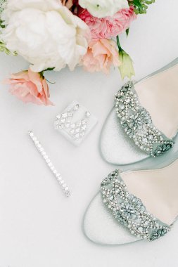 Zarif mücevherler ve yumuşak renklerde taze çiçeklerle süslenmiş göz kamaştırıcı gelinlik ayakkabıları..