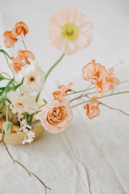 Küçük bir vazodaki yumuşak renkli çiçeklerin güzel bir görüntüsü onların zarafetini ve çekiciliğini basit bir ortamda ön plana çıkarıyor..