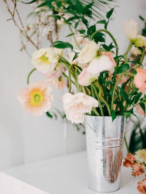 Gümüş bir vazodaki pastel çiçekler minimalist bir iç mekanı aydınlatır, doğanın zarafetini ve tazeliğini gösterir..