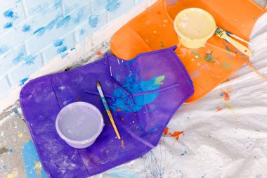 Parlak renkler odayı dolduruyor. Boya malzemeleri zemini canlı bir sanat projesiyle dağıtıyor..