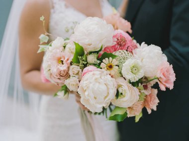Canlı beyaz ve pembe buketli gelin açık hava düğün törenine hazırlanıyor..