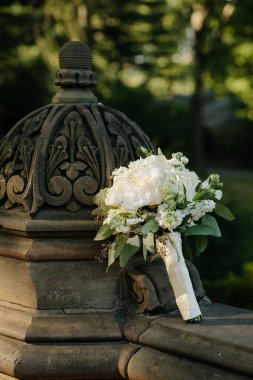 Güzel bir buket beyaz çiçek yeşil bir park ortamındaki dekoratif bir taşın üzerine konur..