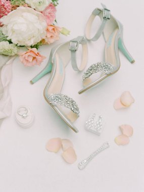 Çiçekler ve mücevherlerle zarif düğün ayakkabıları sergilenir. Özel bir durum için romantik bir ortam yaratır..