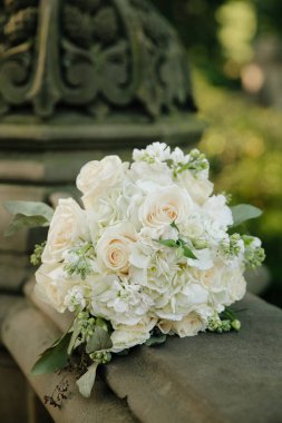 Zarif bir buket beyaz gül ve yeşillik canlı bir bahçe ortamında, taş bir yüzeyde sergilendi..