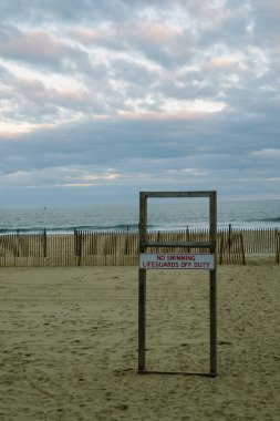 Sahilde duran bir tabela, gece ışığında cankurtaranların izinli olduğu için yüzmeye izin verilmediğini gösteriyor..