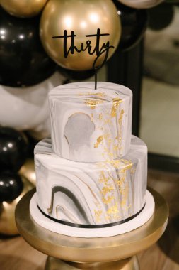 İki katlı güzel bir pasta mermer desenler ve altın aksanlı bir doğum gününü kutlar..