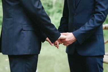 Erkekler doğal ışık altında huzurlu bir bahçede el ele tutuşurken yemin ederler..