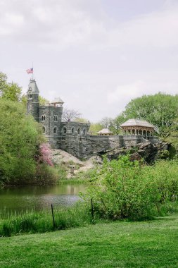 Büyüleyici bir taş kale, bereketli ağaçlar ve çiçek açan çiçeklerle çevrelenmiş sakin bir gölete bakar..