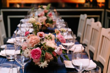 Şık bir restoranda taze çiçekler ve pırıl pırıl cam eşyalar içeren güzel bir yemek masası..