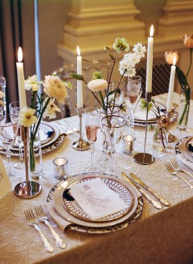 Güzel bir masa, özel bir durum için zarif sofra takımı, çiçek dekoru ve mum ışığı sergiler..