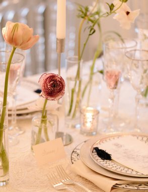 Enfes bir yemek masası. Taze çiçekler, zarif cam eşyalar ve özel bir gün için yumuşak mum ışığı..