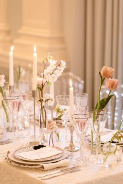 Cam eşyalar, narin çiçekler ve sıcak bir atmosfer yaratan mumlarla güzel bir şekilde düzenlenmiş yemek masası..