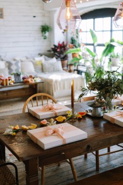 Hediye kutuları, taze çiçekler ve dilimlenmiş meyvelerle dolu güzel bir masa parlak, davetkar bir arka plana karşı..