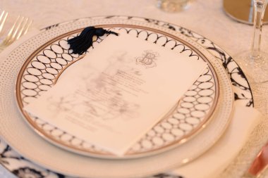 Exquisite table arrangement highlights a stylish menu placed on an ornate plate at an upscale event.