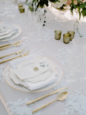 Güzelce düzenlenmiş masa narin çiçek tabakları, altın kaplar ve kristal cam eşyalar ile çevrili bir bahar toplantısı için büyüleyici bir atmosfer yaratıyor..