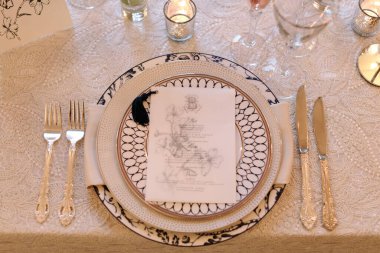 Sofistike bir masa düzenleme özelliği porselen, gümüş çatal bıçak ve şık bir toplantıda detaylı bir menü..