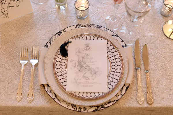 Sofistike bir masa düzenleme özelliği porselen, gümüş çatal bıçak ve şık bir toplantıda detaylı bir menü..