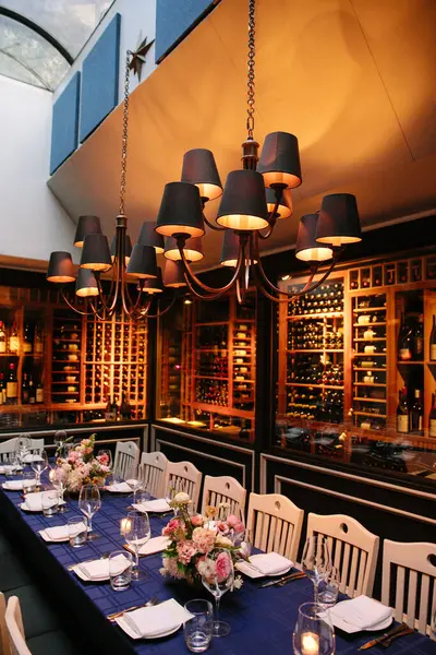 Çiçekli ve mumlu güzel bir yemek masası şık bir restoranda bir avizeyle aydınlatılır..