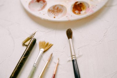 Sanatsal araçlar canlı renkler ve yaratıcılığı vurgulayan karıştırıcı bir palet ile dokulu tuval üzerinde düzgün bir şekilde görüntülenir.