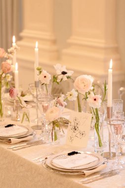 Zarif bir kutlama için çiçekler, mumlar ve güzel yemek takımlarıyla güzel bir yemek masası..