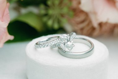 Parlak alyanslar, narin çiçeklerle çevrili yumuşak beyaz bir yastıkta dinleniyor. Aşkı ve bağlılığı simgeliyor..