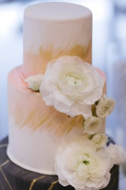 Zarif beyaz çiçekler ve yumuşak pastel renklerle süslenmiş göz kamaştırıcı bir düğün pastası..