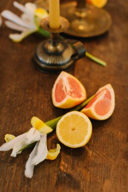 Dilimlenmiş turunçgiller ve taze çiçekler eski ahşap bir yüzey üzerinde renkli bir görüntü oluşturur..