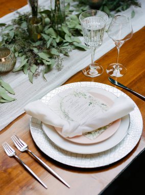 Güzel düzenlenmiş bir yemek masasında taze yeşilliklerle çevrili güzel porselenler ve pırıl pırıl cam eşyalar sergilenir. Bir olay kutlaması için ortam karmaşıktır..