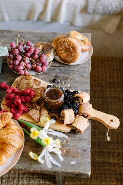 Hamur işleri, meyveler ve reçel ahşap bir masada ustalıkla düzenlenir ve davetkar bir hava yaratır..